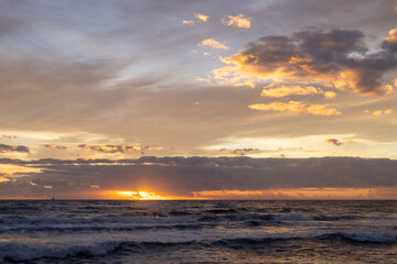 Obraz premium Golden Sunrise Breaking Through Clouds Over Ocean