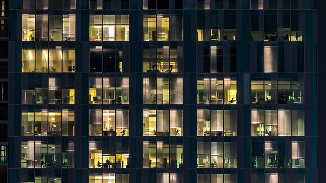 window of the multi-storey building of glass and steel lighting and people within timelapse