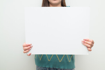 Portrait of a young Asian woman against white background showing copy space placard