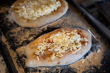 Freshly baked flatbread topped with cheese on a baking tray ready for the oven