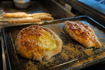 Freshly baked flatbreads with golden crusts on a baking tray in a warm kitchen environment