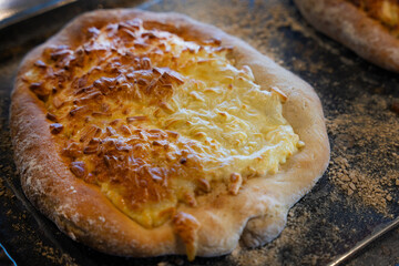 Freshly baked bread with golden crust and melted cheese on a baking tray in a cozy kitchen