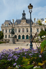 Historic H&ocirc;tel de Ville of Vannes featuring an ornate fa&ccedil;ade, mansard roofs, sculpted stonework, and a prominent central tower, viewed from a foreground garden that enhances its architectural presence