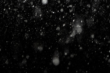 Bokeh effect of snowfall and lights. Abstract blurred background with snowflake in the night sky, White spots and dots in the dark. Snowy stormy weather, falling snow