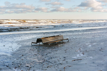 Lonely Wooden Bench on a Sandy Beach with Sea Waves and Clouds, Latvia, Jurmala