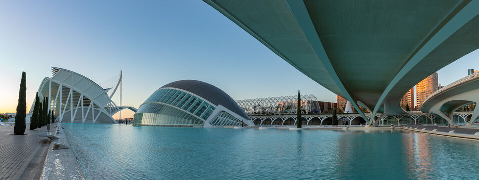Valencia, Spain - March 30, 2025: A panorama of the Hemisferic and the Science Museum Principe Felipe, part of the City of Arts and Sciences, at sunrise, taken from underneath the Montolivet Bridge.