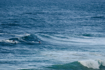 Fototapeta premium Surfers ride powerful ocean waves in an open sea, capturing dynamic water sport action