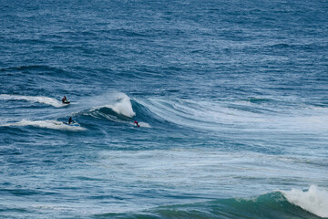 Fototapeta premium Surfers ride large ocean waves in a vibrant blue sea, capturing action and teamwork