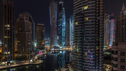 Aerial view of Dubai Marina residential and office skyscrapers with waterfront night timelapse