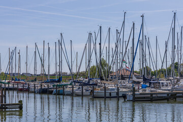 Rows of sailboat masts in a calm harbor in Groningen province. Modern marina under a clear sky with contrails in the Netherlands