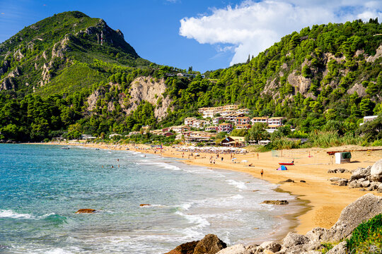 Fabolous Glyfada Beach with tourists on Ionian island Corfu, Greece, popular tourist destination. Green island with mountains.
