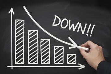 Hand drawing a downward trend arrow on a chalkboard, representing financial loss and market failure, for business analysis, Economic crisis concept with a falling sales chart.
