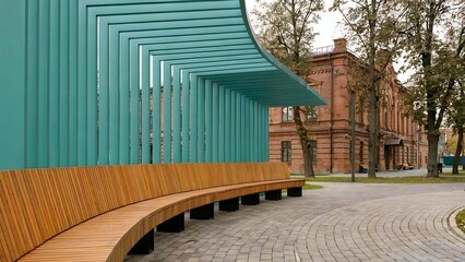 Modern Curved Wooden Bench and Teal Pergola Against Historic Brick Building Facade