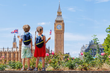 Kids hold UK flags, viewing Big Ben under clear skies, London