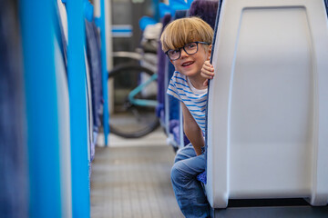 Cheerful child in glasses on train sticking out of wagon seat