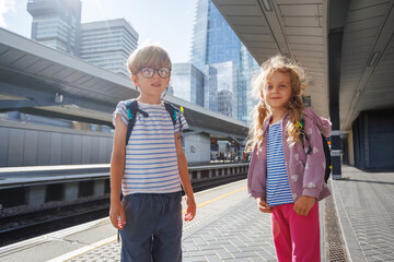 Kids passengers waiting at a modern train station on sunny day