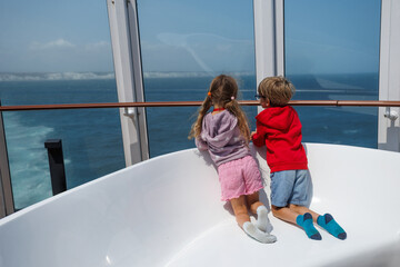 Kids gaze through window at sea, enjoying the view of coastline