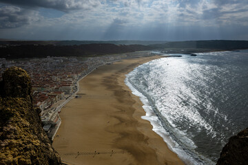 Aerial view of a coastal town and long sandy beach under sunlit ocean light