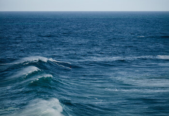 Surfers ride large ocean waves in deep blue sea, a dramatic coastal seascape with motion and energy © .shock
