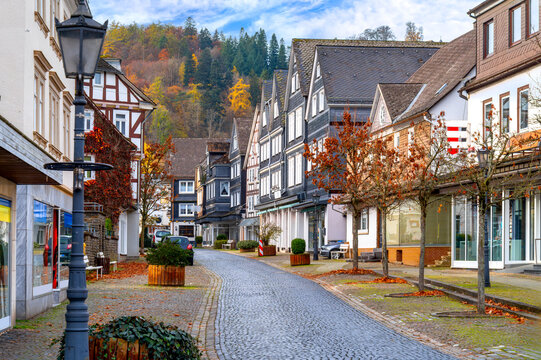 Bad Laasphe, Siegen-Wittgenstein, historic old town street with timber houses, paved road, shop windows and autumn trees in background