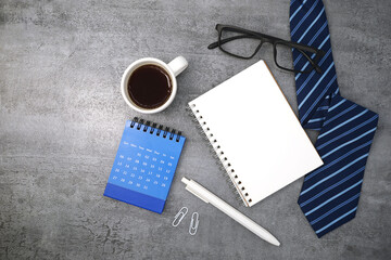 Necktie with glasses and calendar on stone texture background. Business desk office. Top view
