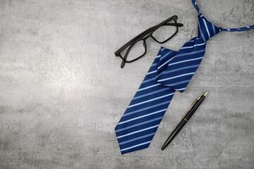 Necktie with glasses on stone texture background. Business desk office. Top view