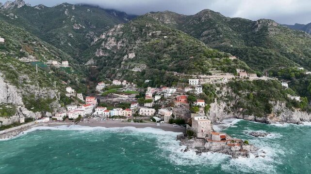 Aerial view of the vibrant Erchie beach with its historic coastal tower, set against the turquoise sea and rocky cliffs, Erchie, Amalfi Coast, Italy.