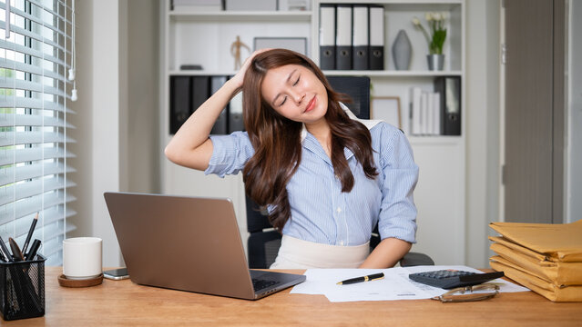 Businesswoman doing a neck stretch exercise at her desk during work hours.