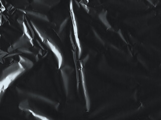 Wrinkled plastic wrap texture on a black background. Cellophane package wallpaper