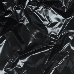 Wrinkled plastic wrap texture on a black background. Cellophane package wallpaper