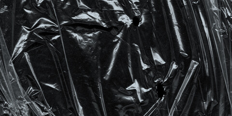 Wrinkled plastic wrap texture on a black background. Cellophane package wallpaper