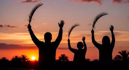 TITTLE: Silhouettes of a man, woman, and child raising palm branches during a sunset. Palm Sunday ceremony or Easter religious celebration. Family worship.