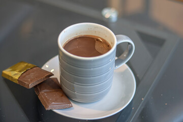 A serving of hot chocolate drink accompanied by a chocolate bar.