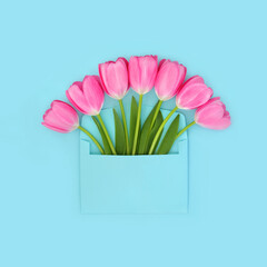 Purple tulip flowers with envelope on blue background. Surreal abstract design surprise for birthday, anniversary, Spring, Beltane, Easter celebration, Mothers Day.
