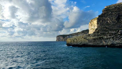 Coastal limestone cliffs and calm sea under clouds in Gozo, Malta