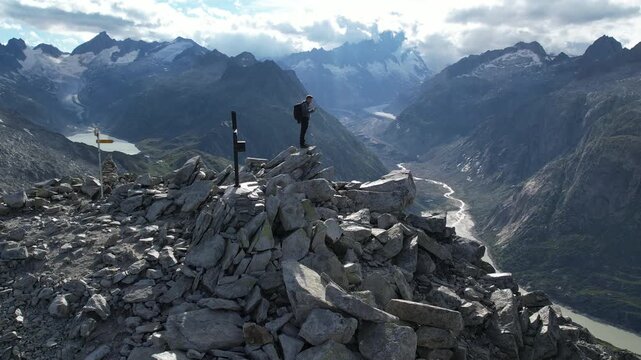 Cinematic Drone Shot of Man Standing on Rocky Mountain Summit in Swiss Alps &ndash; Freedom, Adventure and Epic Alpine Panorama