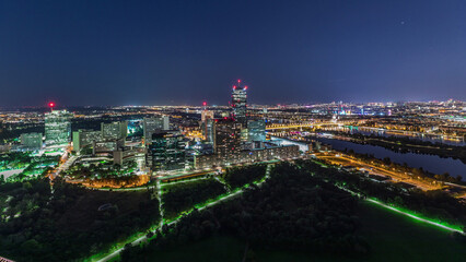 Aerial panoramic view over Vienna city with skyscrapers, historic buildings and a riverside promenade day to night timelapse in Austria.