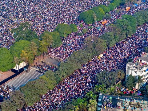 Dhaka, Bangladesh - 31 December 2025: Aerial view of a sea of people flowing through the city streets, a vibrant pulse amidst the concrete and green canopy.