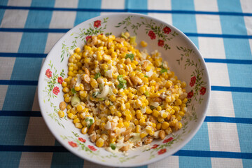 Creamy sweet corn salad with peanuts and green onions in floral bowl
