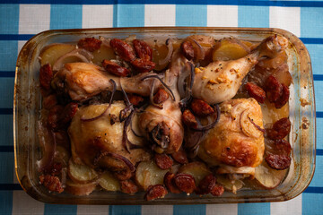 Roasted chicken drumsticks with chorizo and potatoes in glass baking dish