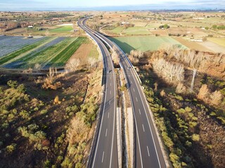 Highway runs through fields and farms in rural area during daylight in autumn season