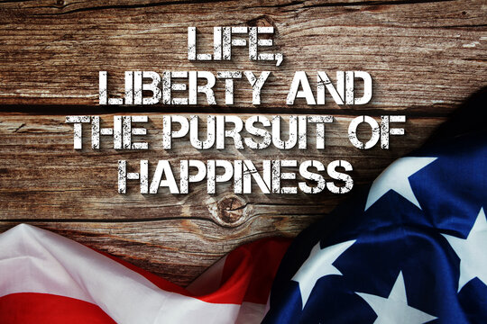 Life, Liberty And The Pursuit Of Happiness text message with USA flag on wooden background