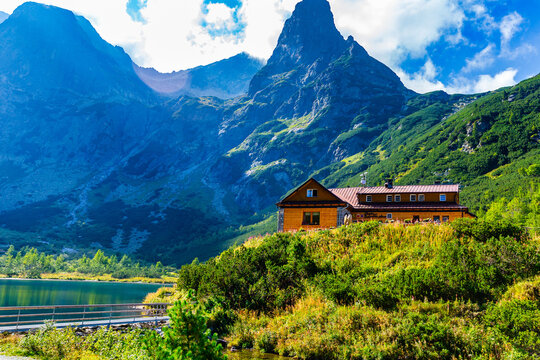 A detailed view of the iconic wooden mountain hut "Chata pri Zelenom plese" situated under steep rocky peaks. Surrounded by lush green pine shrubs and wild meadows in the Tatra National Park, Slovakia