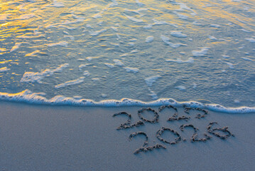 2025 and 2026 written on the sand and 2025 is erased by a small wave
