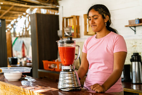 Woman preparing fresh fruit smoothie in rustic cafe - Powered by Adobe