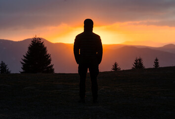 Sylwetka mężczyzny stojącego samotnie na tle pięknego zachodu słońca w górach © RTEKA