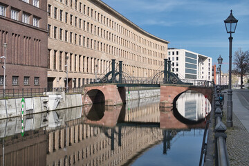 Eiserne Br&uuml;cke and Reflections in Berlin - Calm morning view of the historic Eiserne Br&uuml;cke (Iron Bridge) and old buildings perfectly reflected in the Kupfergraben canal in Berlin, Germany.