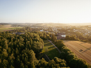 L&auml;ndliche Landschaft mit Dorf, Feldern und Windr&auml;dern im Abendlicht