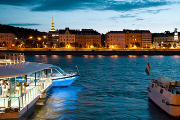 Pier and sightseeing boat against old city at night