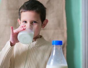 Young Boy in Ribbed Sweater Drinking a Glass of Fresh Milk at Breakfast